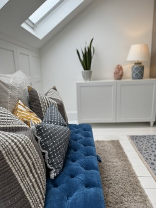 A blue ottoman with scatter cushions in a brightly lit therapy room.